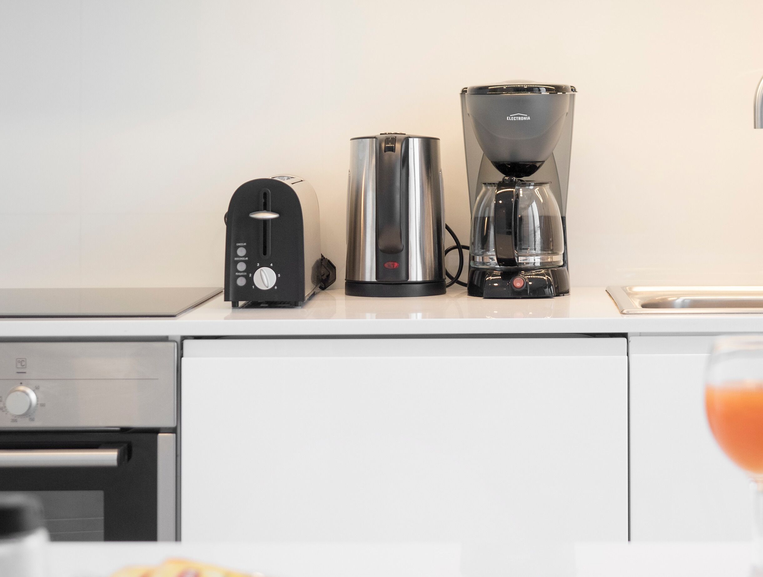 A kitchen with a toaster, a coffee maker, and a kettle on the counter.