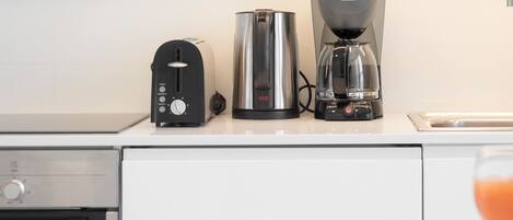 A kitchen with a toaster, a coffee maker, and a kettle on the counter.