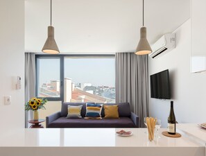 Een moderne woonkamer met een bank, een televisie en een eethoek, met een fles wijn.