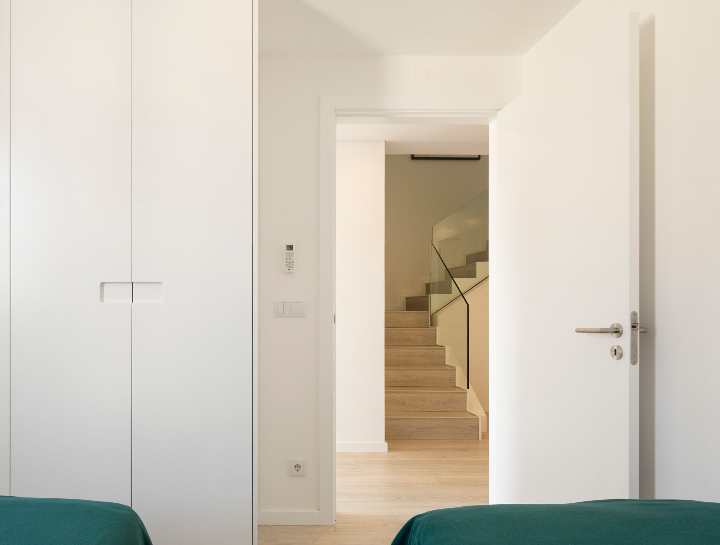 Una camera moderna con un letto, una porta e una scala che conduce ad un'altra zona.
