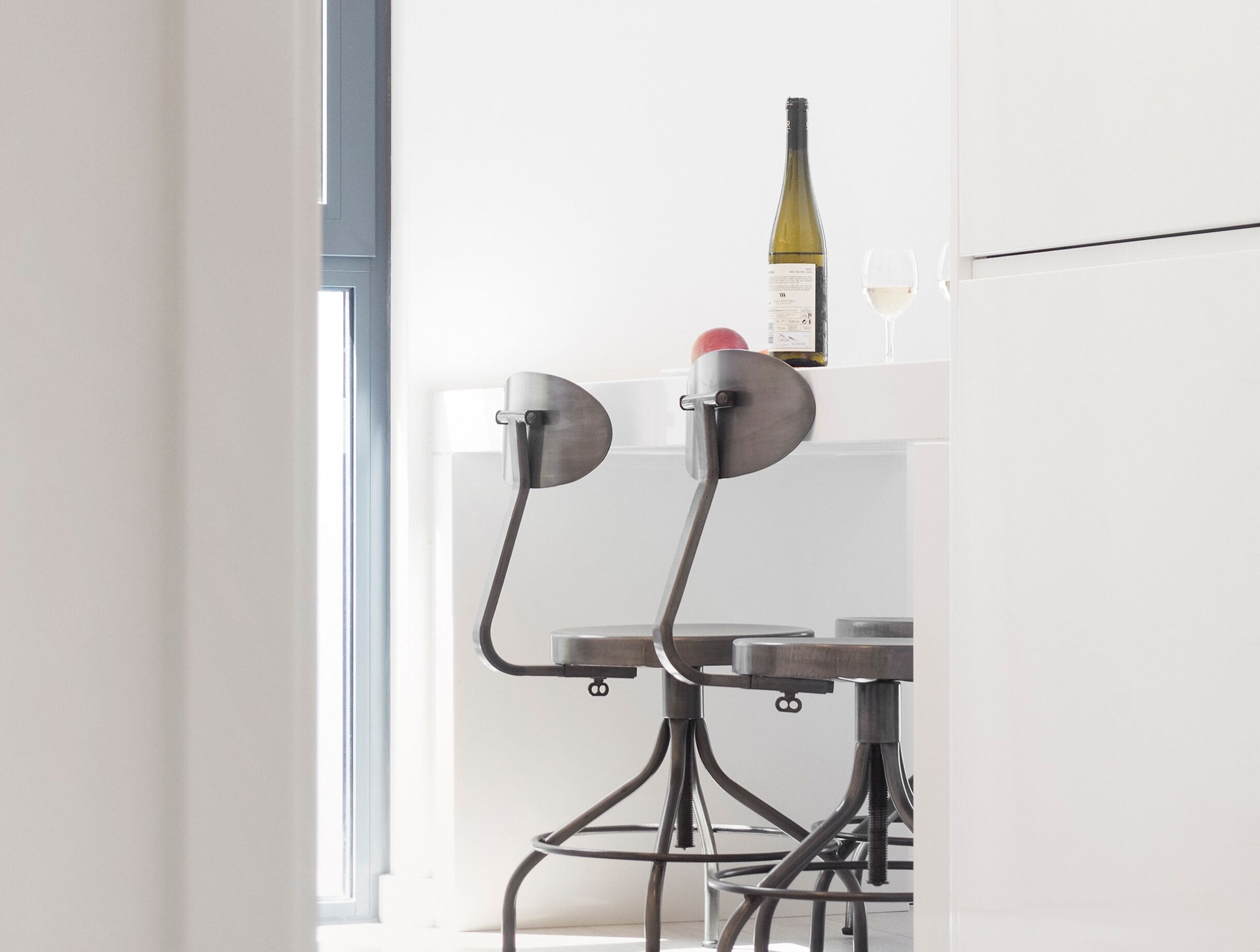 Un área de comedor con una mesa y sillas, una botella de vino y una copa sobre la mesa.