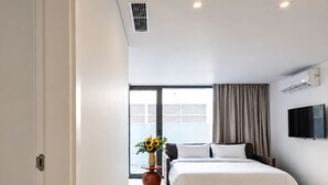 Una habitación de hotel moderna con una cama, televisión y ventana con cortinas.