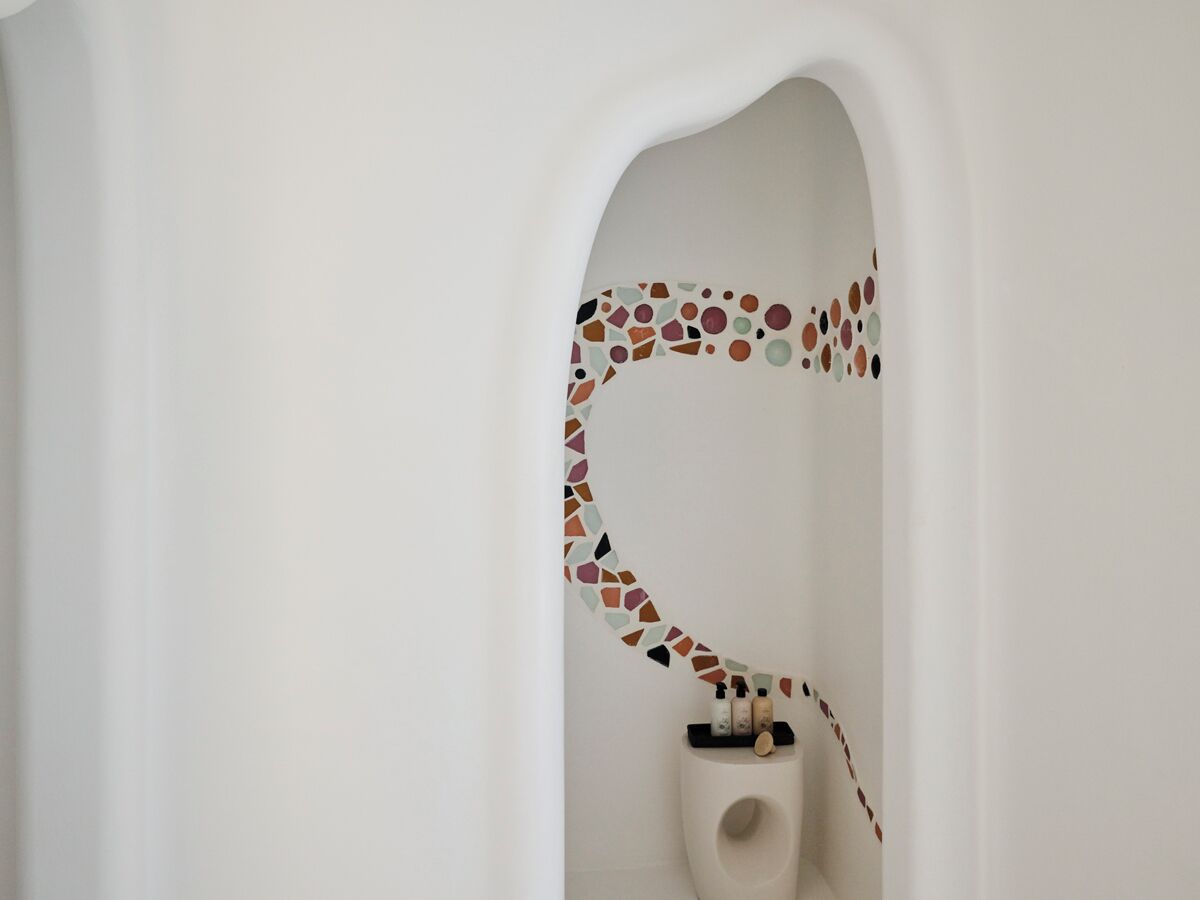 Ein Badezimmer mit weißer Wand und einem Mosaikfliesenmuster in der unteren Hälfte.