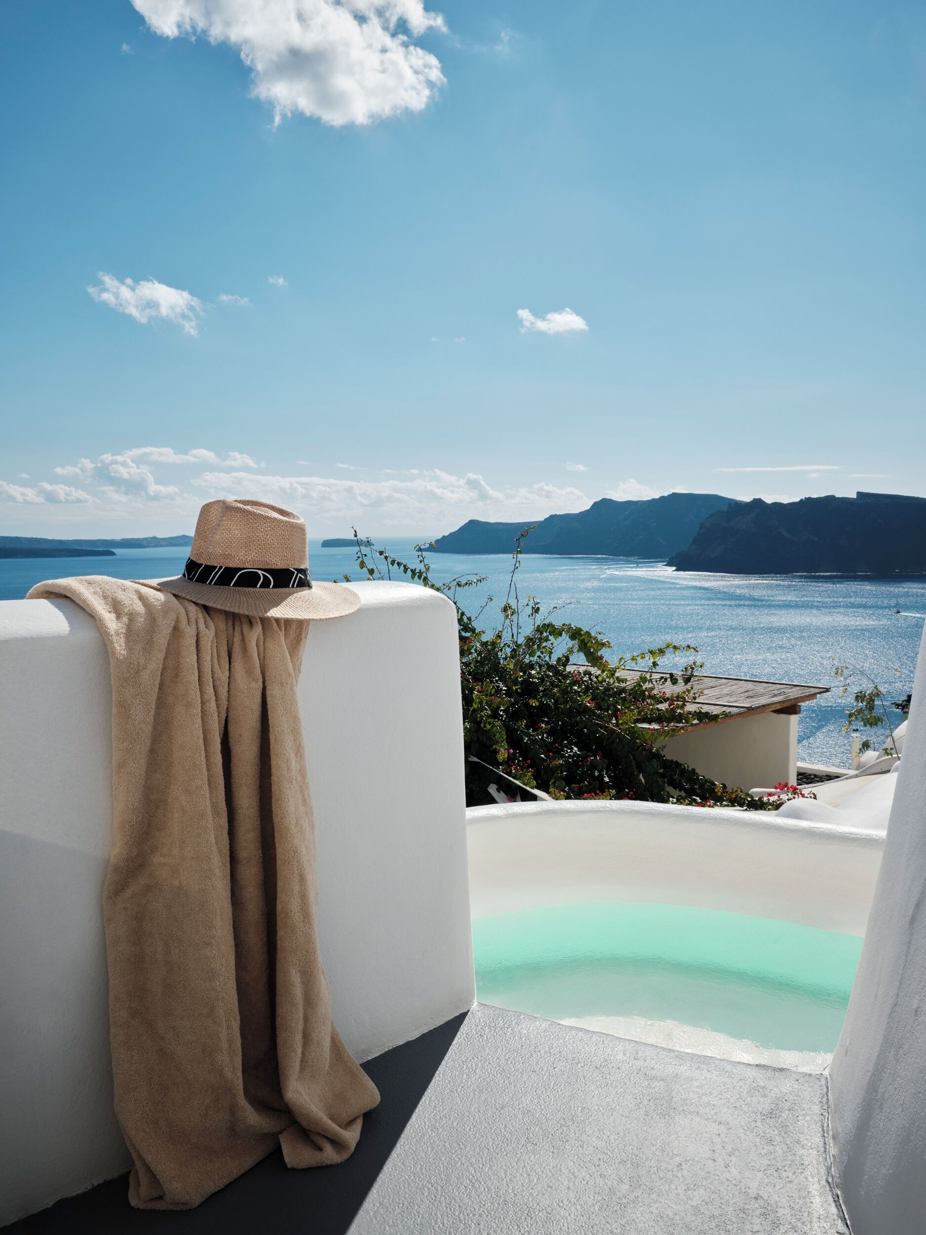 A white infinity pool with a clear view of the sea and distant mountains.