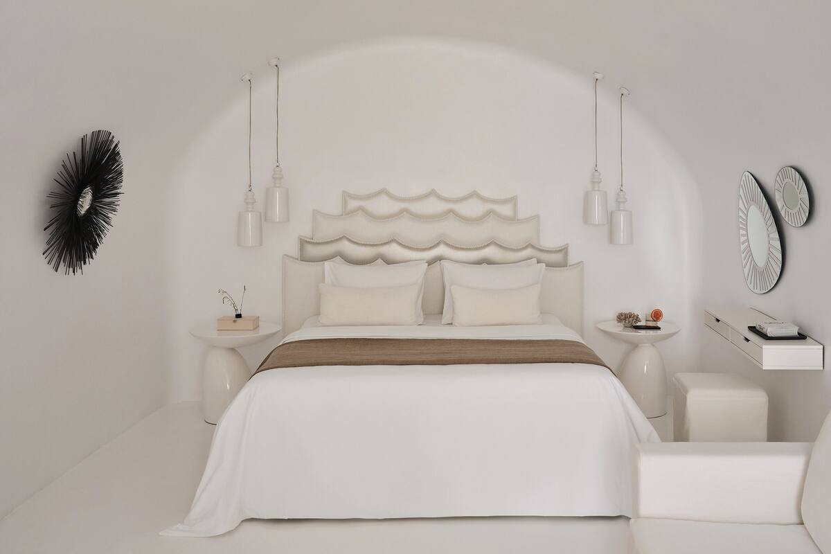 A minimalist bedroom with a large bed, bedside tables, and a small seating area.