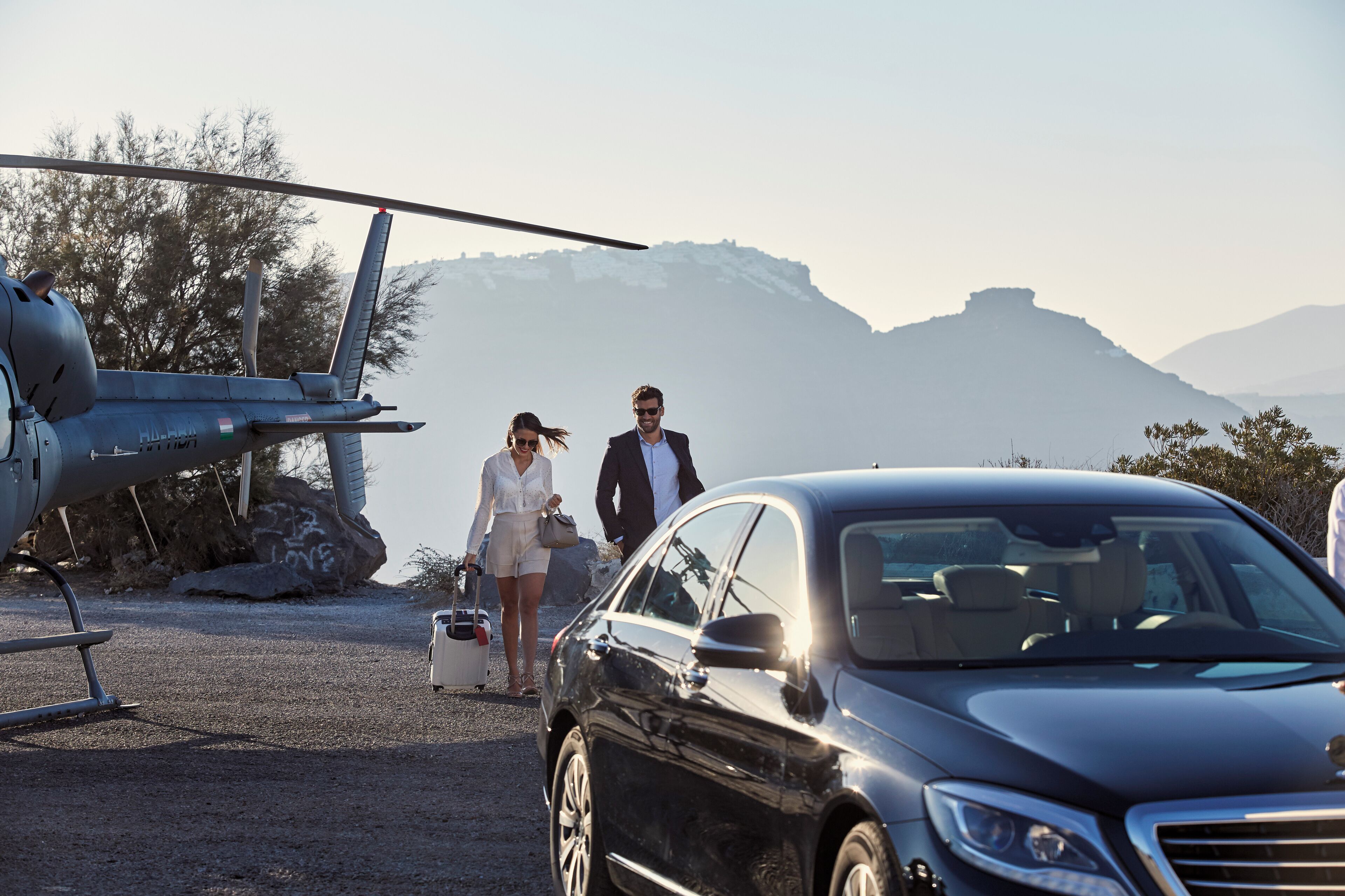 A helicopter parked on a gravel surface with a car nearby.