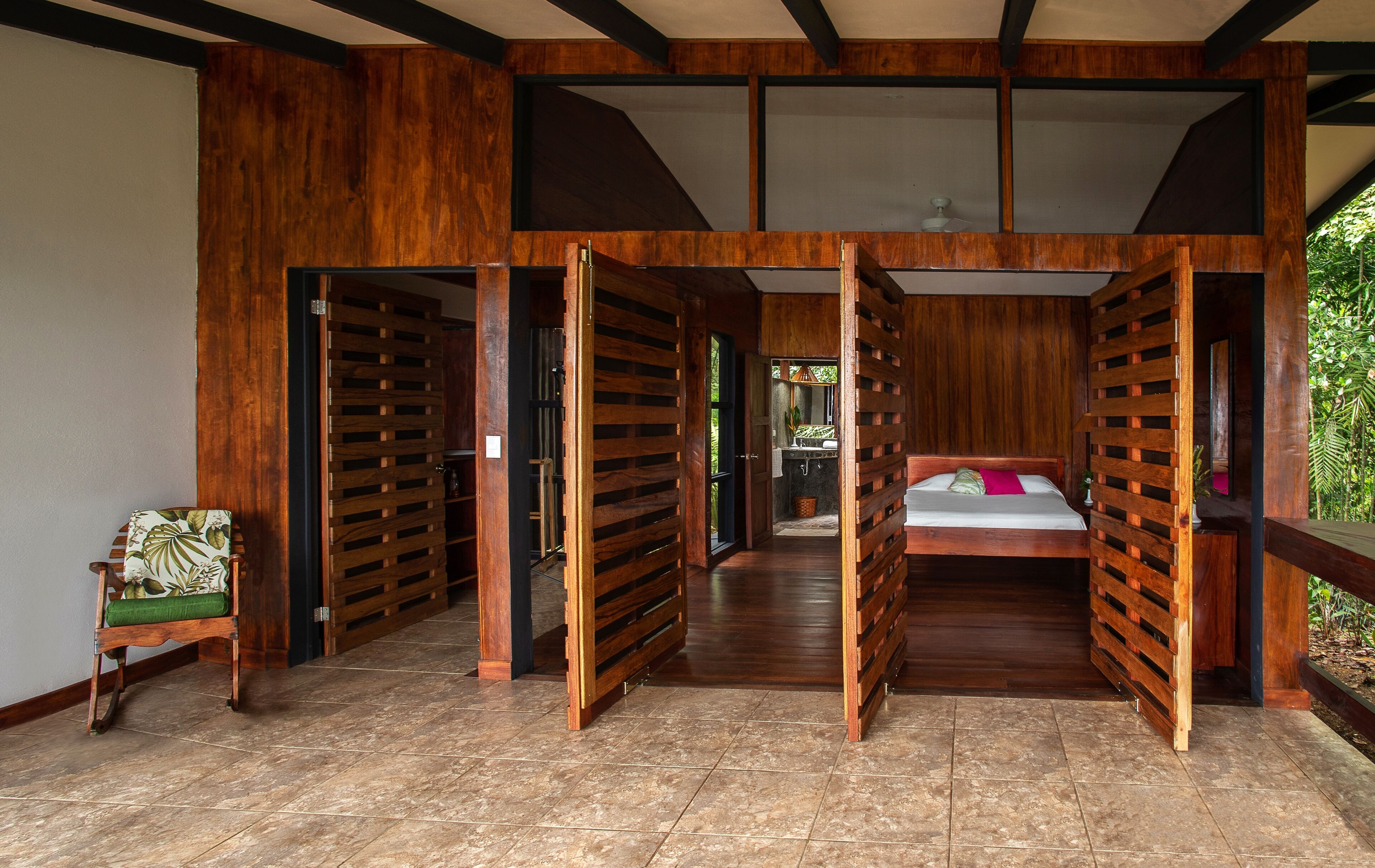 Una habitación con cama, un armario de madera y un pequeño rincón de descanso.