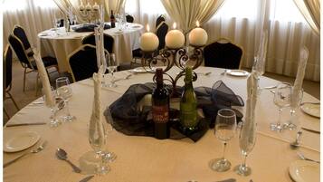 Una mesa de comedor dispuesta con copas de vino, platos y cubiertos, con velas y botellas de vino.