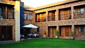 A courtyard with a dining area, stone walls, and a covered seating area. - Alveston Manor (Middelburg)