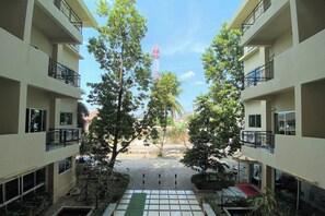 A multi-story building with balconies, a central courtyard, and a view of a red tower in the distance. - C.a.p. Mansion Hotel by Zuzu (Wichit)