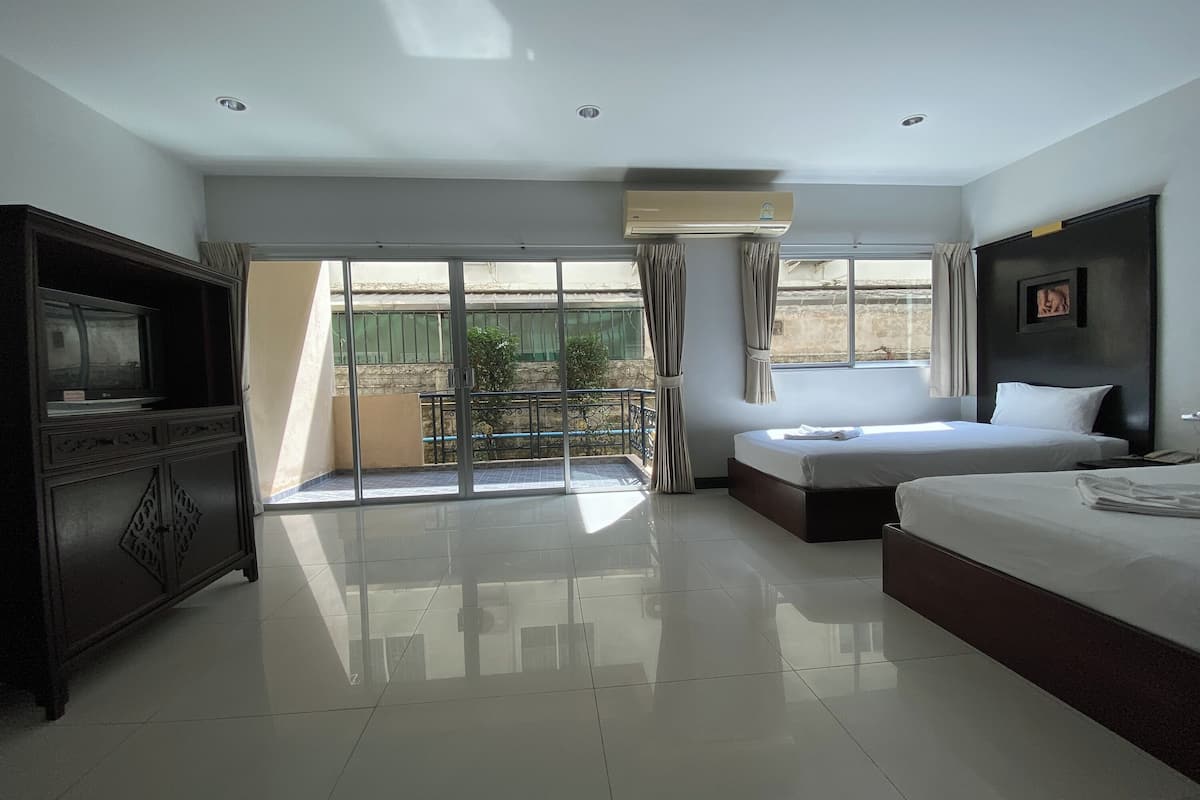 A hotel room with a large bed, a TV, a wardrobe, and a balcony with a view.