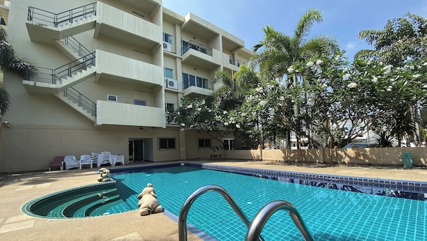 A swimming pool with a tiled edge, a multi-story building with balconies, and palm trees. - C.a.p. Mansion Hotel (Wichit)
