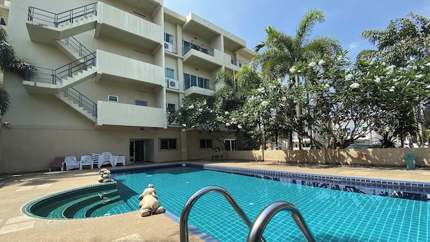 A swimming pool with a tiled edge, a multi-story building with balconies, and palm trees. - C.a.p. Mansion Hotel (Wichit)