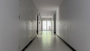 A long, narrow hallway with white walls and a tiled floor, leading to a door at the end. - C.a.p. Mansion Hotel (Wichit)