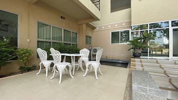 A building with a balcony, white outdoor furniture, and potted plants.