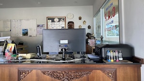 A reception desk with a computer, a clock, and a calendar on the wall. - C.a.p. Mansion Hotel (Wichit)