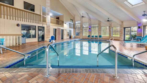 An indoor swimming pool with a tiled floor, metal railings, and a high ceiling with skylights.
