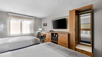 Ett hotellrum med två sängar, ett skrivbord, en tv och en garderob.