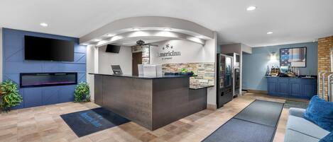 A reception area with a counter, a flat-screen TV, and a sign that reads 'AmericInn by Hyatt.'