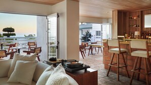 A modern living room with a sofa, a coffee table with a record player, and a view of the ocean. - Hotel Joaquin (Laguna Beach)