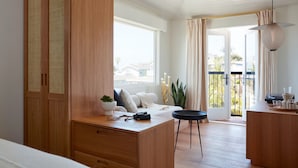 A modern room with a wooden wardrobe, a sofa, a dining area, and a balcony with a view. - Hotel Joaquin (Laguna Beach)