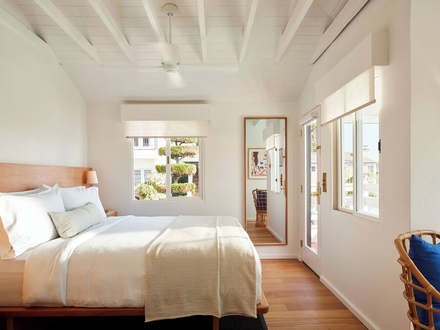 A bedroom with a bed, a nightstand, a window, and a door.