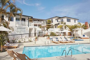 A poolside area with lounge chairs, umbrellas, and a clear blue pool. - Hotel Joaquin (Laguna Beach)