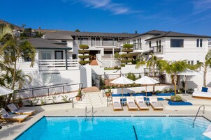 Una piscina al aire libre, sombrillas, sillones reclinables de piscina