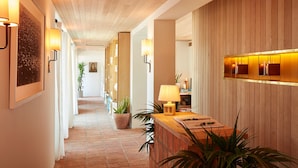 A hotel lobby with a wooden ceiling, a reception desk, potted plants, and wall-mounted lamps. - Hotel Joaquin (Laguna Beach)
