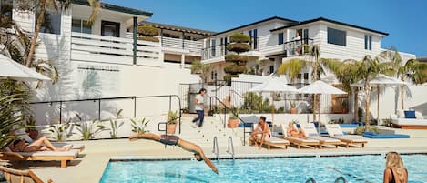 Una piscina al aire libre, sombrillas, sillones reclinables de piscina