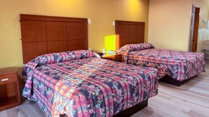 Une chambre d’hôtel avec deux lits, des têtes de lit en bois, une table de chevet avec une lampe et une petite commode en bois.