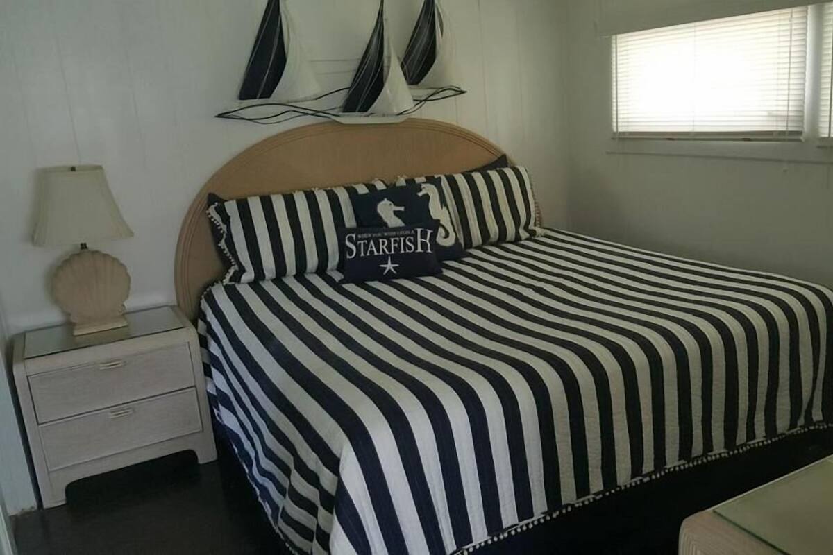Een bed met gestreepte lakens en een kussen met de tekst 'STARFISH'.