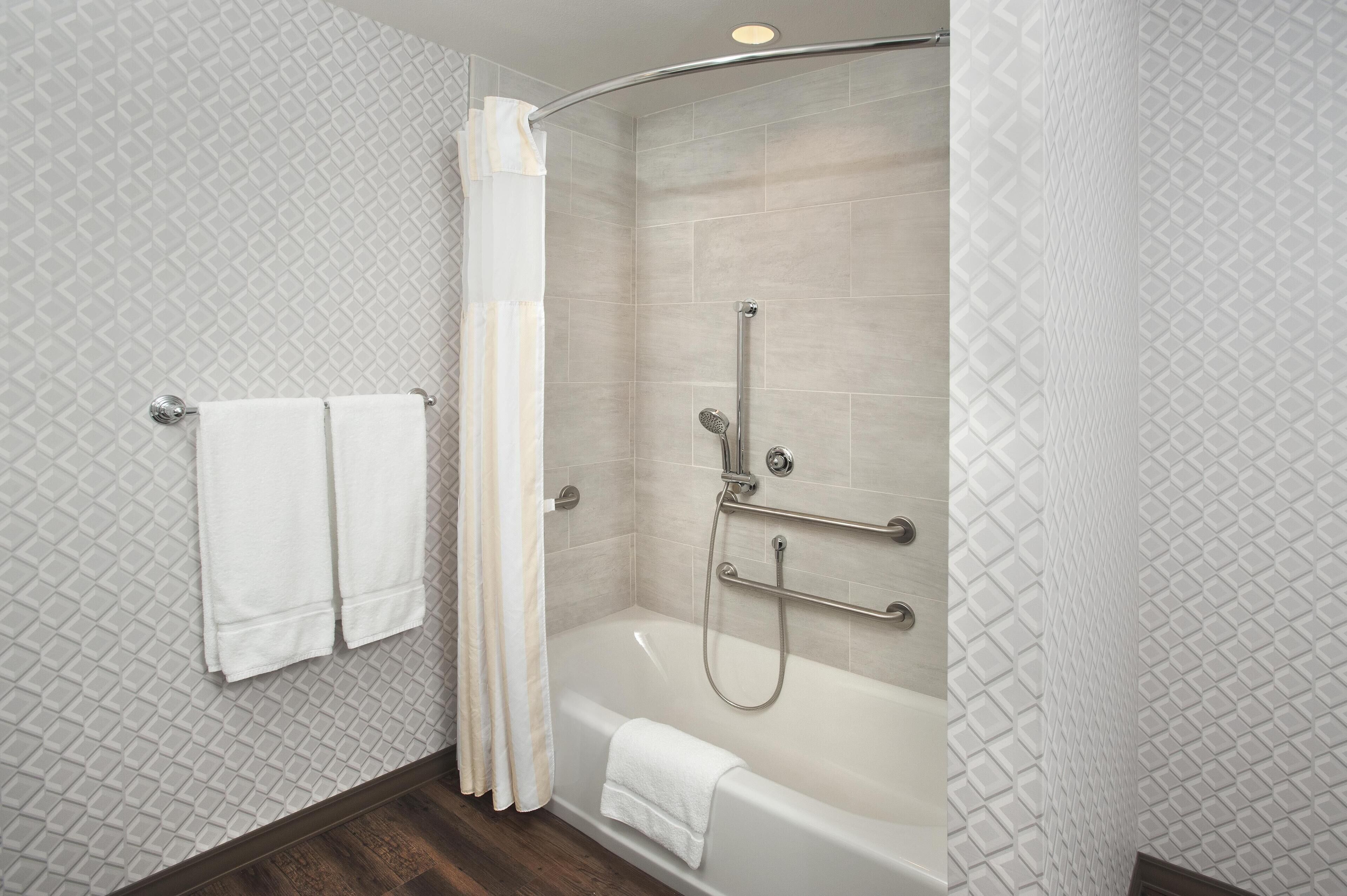 Ein modernes Badezimmer mit begehbarer Dusche, einer Badewanne und einem Handtuchhalter mit zwei Handtüchern.
