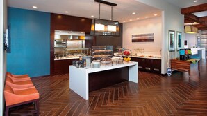 Un hall d’hôtel moderne avec un espace buffet, des sièges et une grande œuvre d’art accrochée au mur.