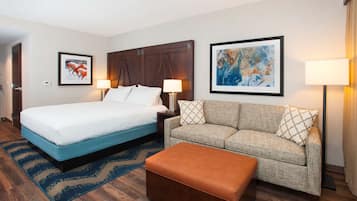 A hotel room with a bed, a sofa, a coffee table, and two lamps.