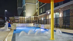 Area piscina esterna con canestro da basket, fontana e edificio con facciata in pietra e numerose finestre.