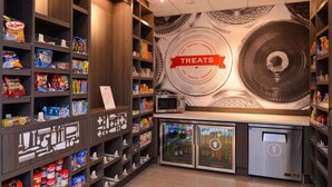 A snack and treat section with shelves stocked with various snacks and beverages, a microwave, and a refrigerator. - Hampton Inn & Suites Albany-East Greenbush (East Greenbush)