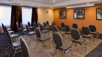 Une salle de conférence avec des rangées de chaises, une horloge et des tableaux accrochés aux murs.