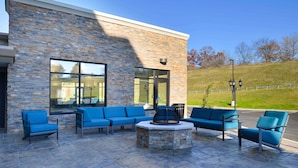 An outdoor seating area with blue sofas and a stone fire pit. - Hampton Inn & Suites Albany-East Greenbush (East Greenbush)