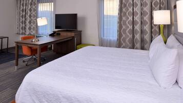 Hotelkamer met een groot bed, een bureau met computer en telefoon, een televisie en twee lampen.