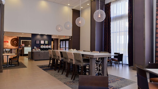 A modern hotel lobby with a dining area, a reception desk, and a bar. - Hampton Inn & Suites Albany-East Greenbush (East Greenbush)