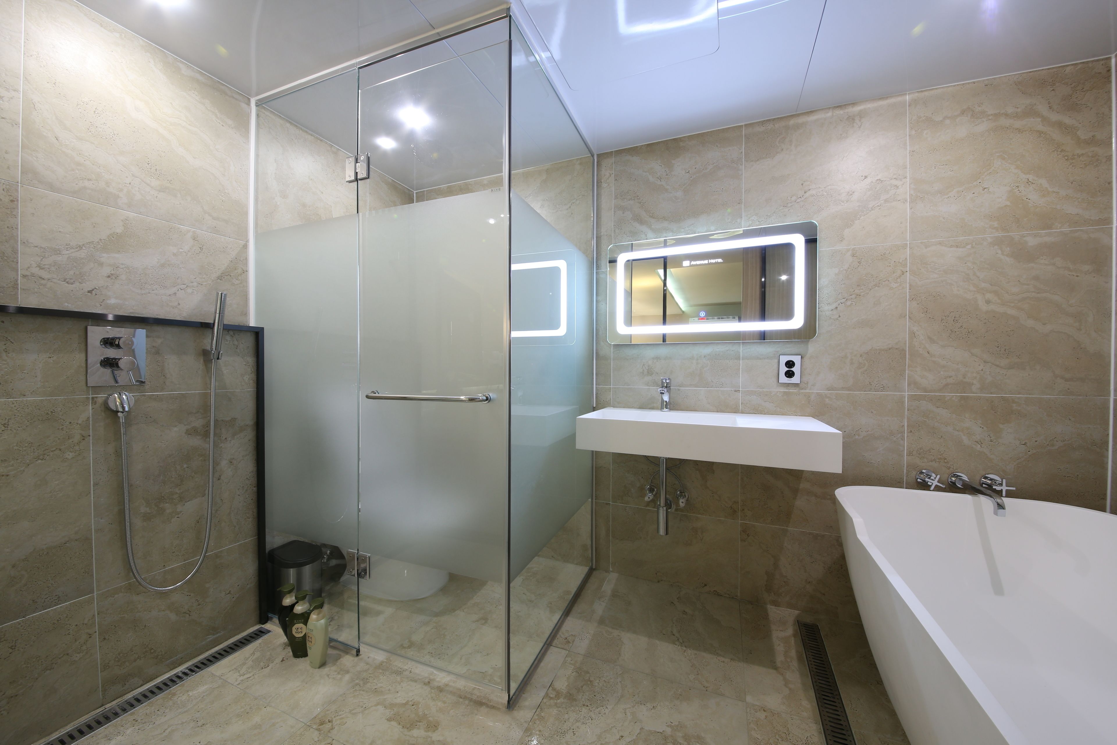 Un baño moderno con ducha de vidrio, lavabo blanco y bañera.