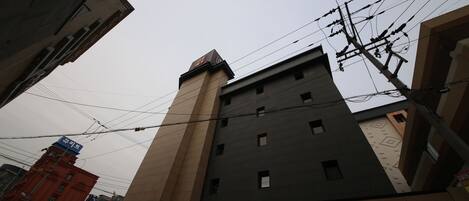 Un edificio de varios pisos con un diseño arquitectónico moderno, que destaca por su estructura en esquina y numerosos ventanales.