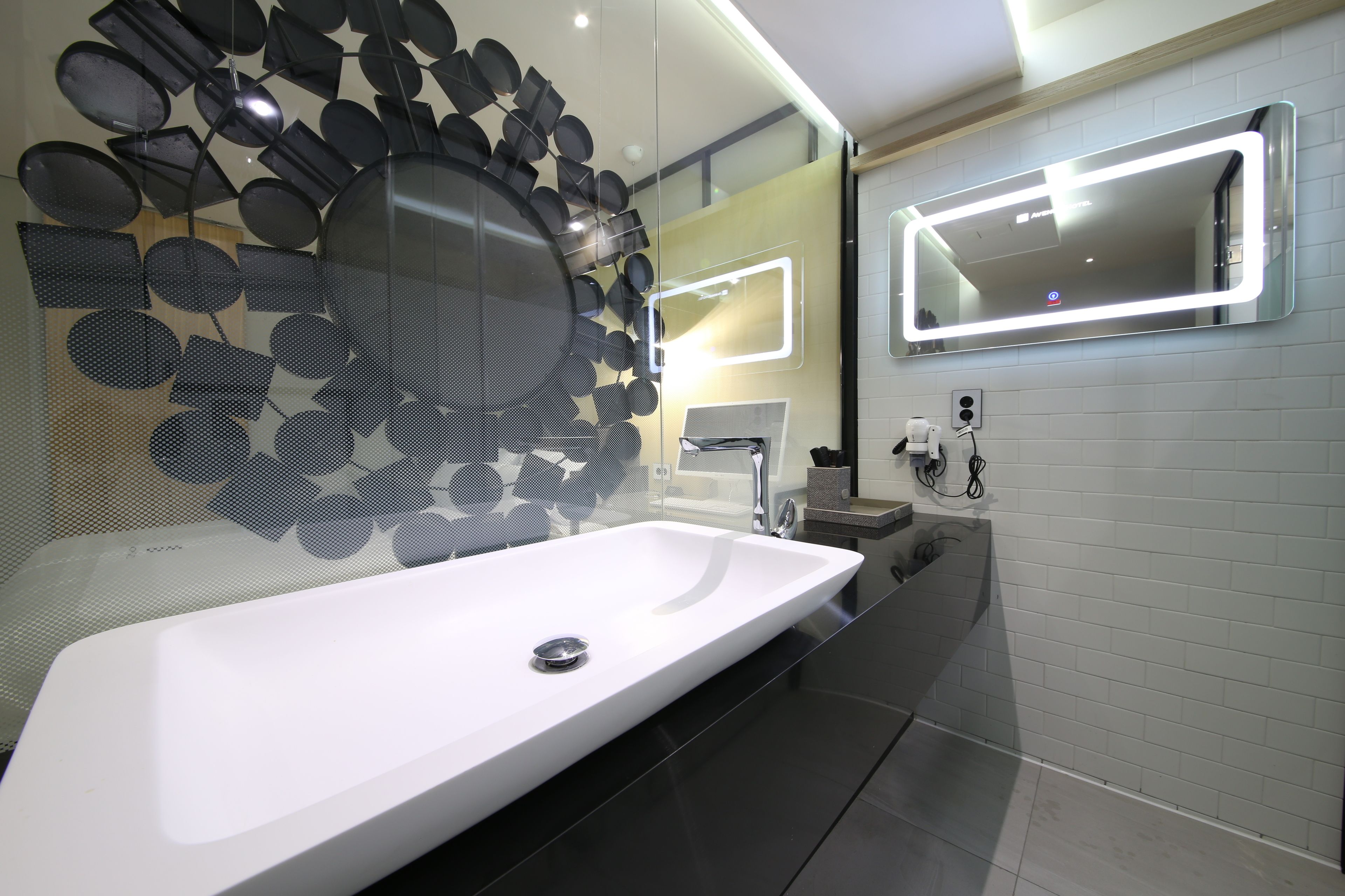 A modern bathroom with a white sink, a large mirror, and decorative wall art.
