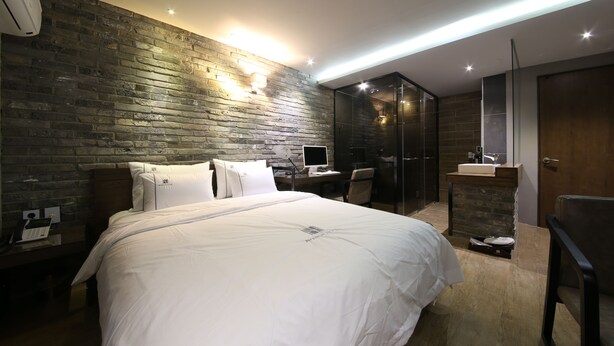 A modern hotel room with a large bed, a desk, a chair, a bathroom, and a wardrobe. - Avenue Hotel (Jeonju)