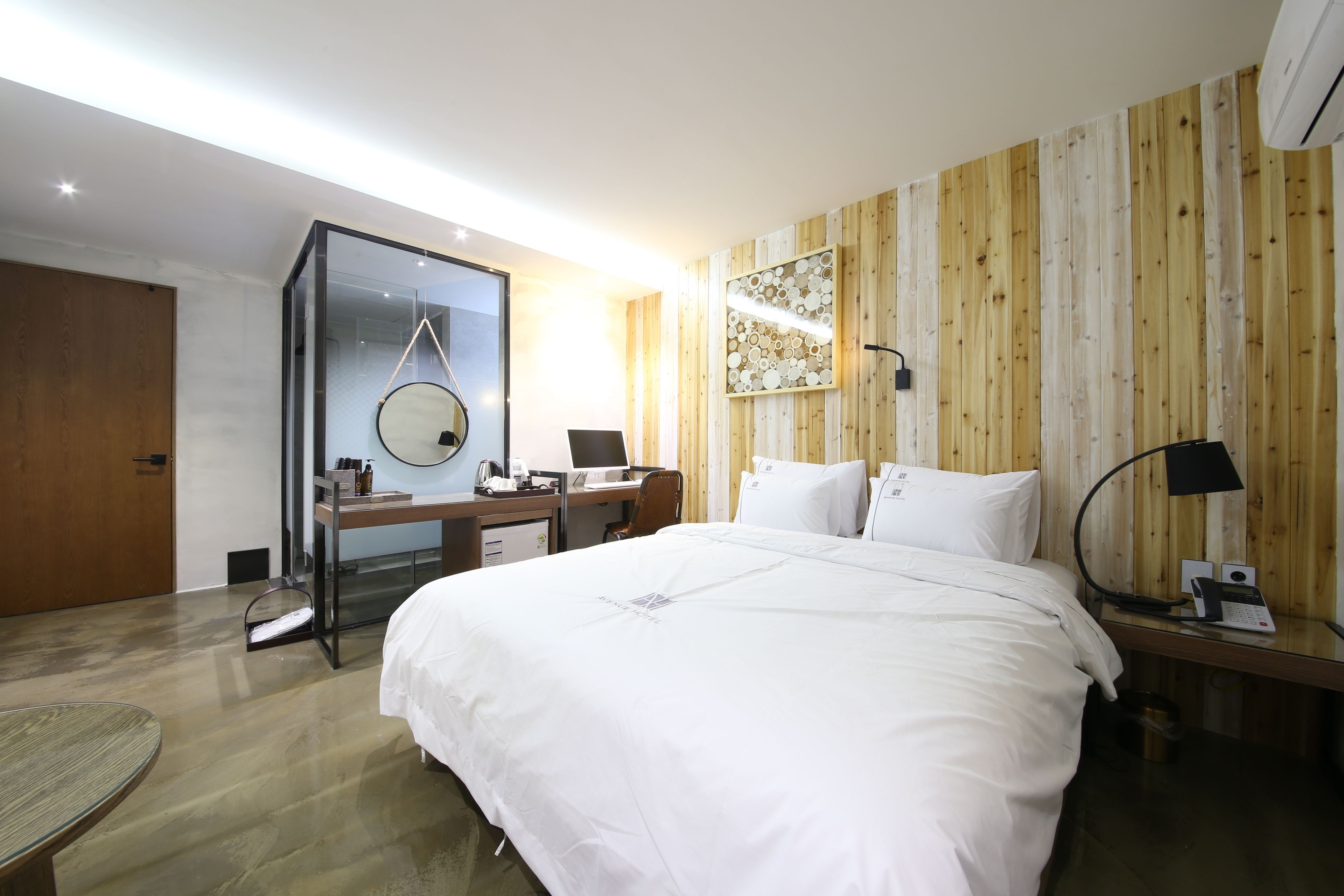 Ein modernes Hotelzimmer mit einem großen Bett, einem Schreibtisch mit Computer, einem Stuhl und einem kleinen Tisch.