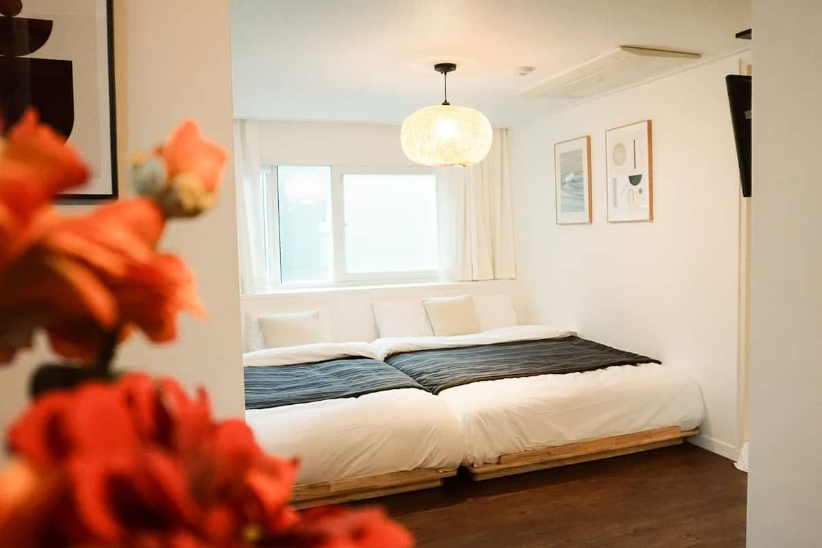 A bedroom with a bed, a window, and a hanging light fixture.