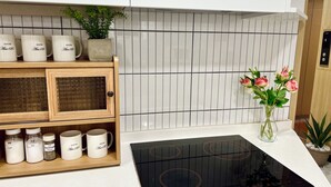 A kitchen with a modern design, featuring a white countertop, a built-in stove, and a cabinet with labeled containers. - ARA125 (Seoul)