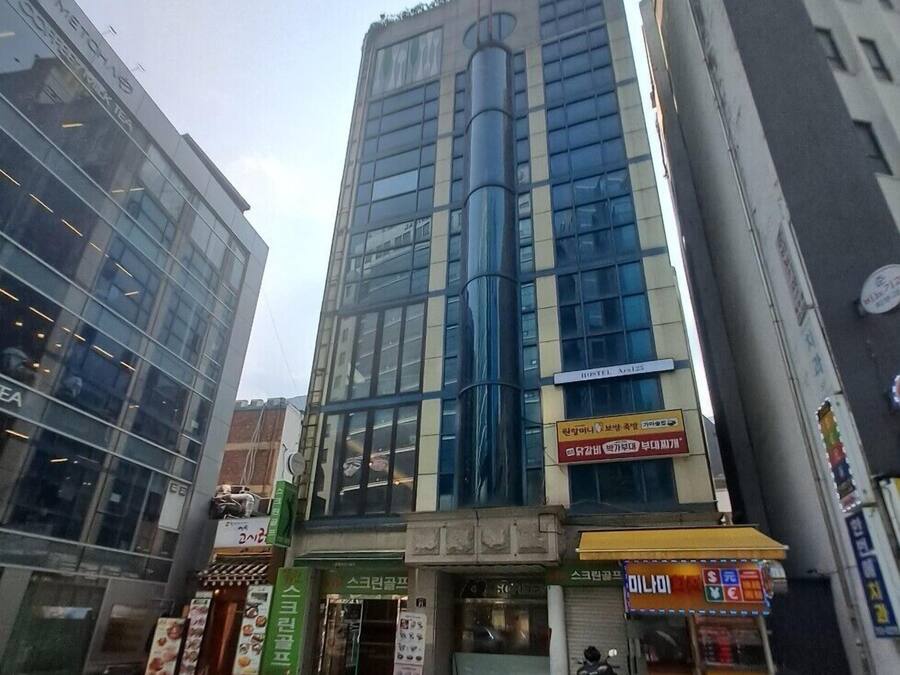 A modern building with a glass facade, a prominent cylindrical structure, and a sign for a hotel named "HOTEL Avia".