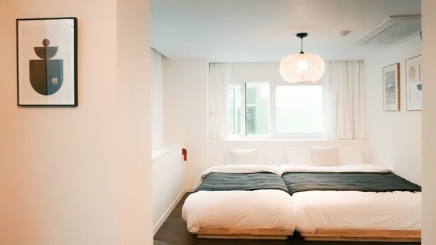A bedroom with a bed, a window, and a hanging light fixture. - ARA125 (Seoul)